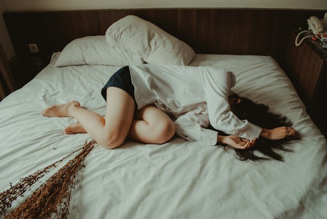 Femme allongée, recroquevillée sur son lit pendant ses règles